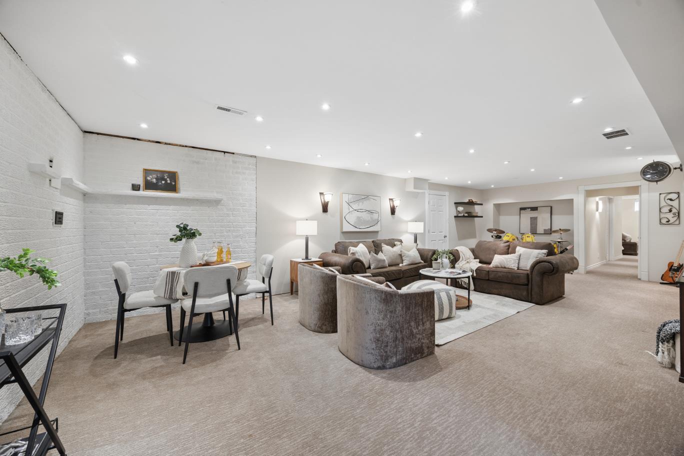 Finished basement recreation room with seating and white brick accent wall at 30 Potters Lane
